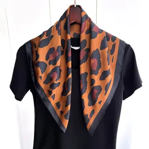 Vista dettagliata di un foulard in seta leopardato su maglia nera e gruccia