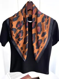 Dettaglio di sciarpa in seta leopardata con bordo nero e maglia nera lavorata