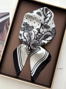 Makro-Detail eines Seidenschals mit Paisley-Muster in Geschenkbox mit elegantem Schwarz-Weiß-Design