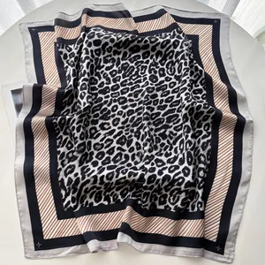 Detailed flat lay of a leopard print silk scarf with striped borders and satin finish