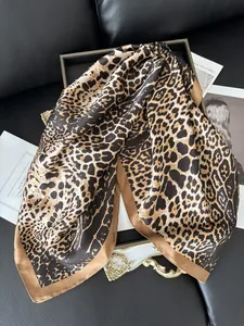 Detail of leopard print silk scarf with glossy satin texture and brown hem on black leather