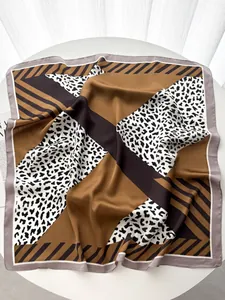 Close-up of a satin square scarf with leopard print and geometric patterns in caramel and black
