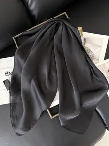 Gros plan d'un foulard en soie satinée noire avec texture brillante et détail doré