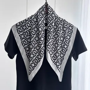 Nahaufnahme eines schwarz-weißen Seidentuchs mit Kettenmuster auf schwarzem T-Shirt