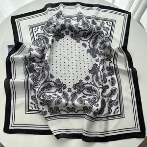 Detail eines Seidenimitat-Halstuchs mit Paisleymuster in Schwarz-Weiß und edlem Faltenwurf
