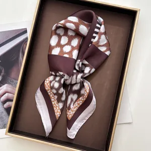 Close-up of leopard print silk scarf with brown and white polka dots in gift box
