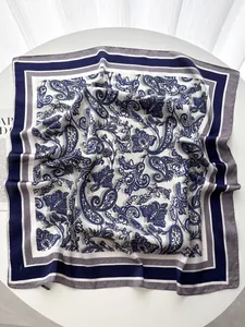 Détail d'un foulard en soie carré avec des motifs cachemire bleu marine et fleurs