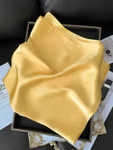 Détail d'un foulard carré en satin jaune brillant avec une texture soyeuse et élégante