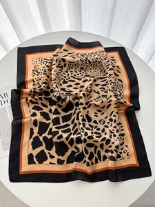 Dettaglio di foulard in seta leopardata con bordo arancione e cuciture fini su tavolo