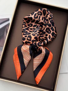 Détail d'un foulard en soie à motif léopard et rayures oranges sur support en cuir