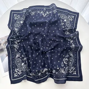 Detail of dark blue paisley silk scarf with white star patterns on a white table