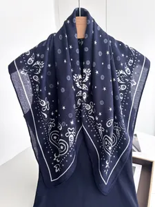 Detailed view of dark blue paisley silk scarf with white star prints on wooden hanger