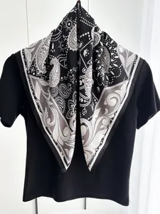 Dettaglio di un foulard in seta di lusso con motivo paisley nero e bianco su t-shirt
