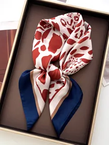 Dettaglio macro di un foulard in seta con stampa leopardata rosso-marrone e bordo blu
