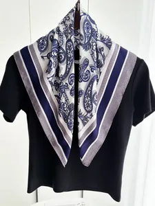 Détail du foulard en soie blanche avec motif paisley et bordures rayées sur haut noir