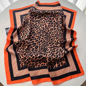 Detailed view of large square silk scarf featuring brown leopard print and vibrant orange borders