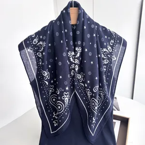 Close-up of navy blue paisley silk scarf with star patterns and frayed edges on a hanger