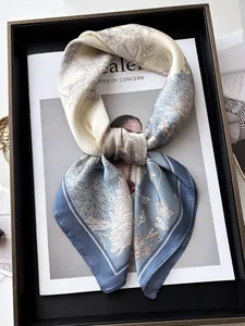 Detail of floral printed silk scarf showing satin texture and contrast hem in a tray
