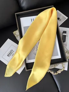 Détail d'un foulard en satin jaune vif avec une texture lisse et un brillant élégant