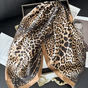 Close-up of leopard print silk scarf featuring a brown border and soft satin texture