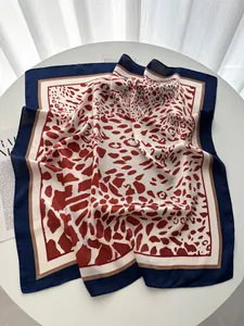 Dettaglio di un foulard in seta leopardato rosso con eleganti bordi blu scuro