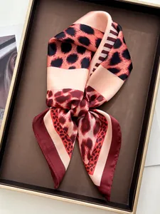 Close-up of a leopard print silk scarf elegantly folded in a decorative gold-rimmed tray