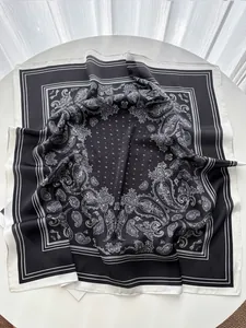 Detailansicht eines schwarz-weißen Paisley-Seidentuchs auf einer minimalistischen Tischplatte