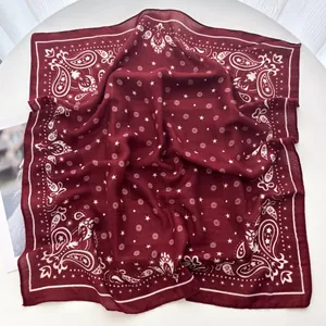 Macro view of burgundy paisley square scarf with delicate star patterns and soft texture