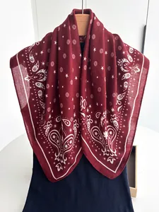 Detail of burgundy square scarf with white paisley patterns and star floral print