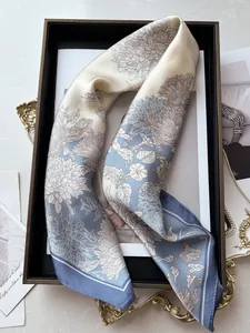 Detailed close-up of light blue and beige silk scarf featuring hand-painted floral patterns