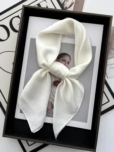 Détail d'un foulard en satin blanc crème au lustre perlé sur un magazine de mode