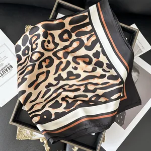 Elegant leopard print square silk scarf with contrast striped borders on a tray