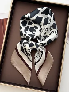 Dettaglio di un foulard di seta con stampa mucca bianca e nera e bordi kaki