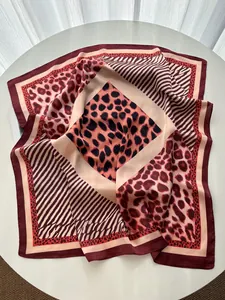 Macro detail of silk leopard print square scarf featuring elegant burgundy and cream tones