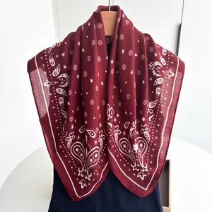 Close-up of burgundy square scarf with paisley and star prints on a wooden hanger