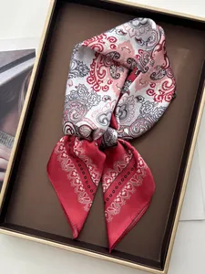 Close-up of red paisley print square silk scarf tied elegantly in a decorative tray