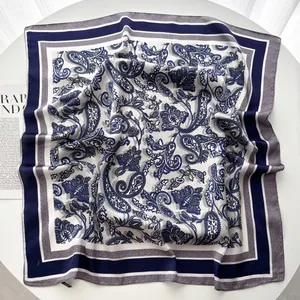 Carré de soie bleu marine et blanc avec motif cachemire posé sur fond blanc