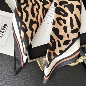 Elegant leopard print satin scarf with black and white striped edges on a textured background