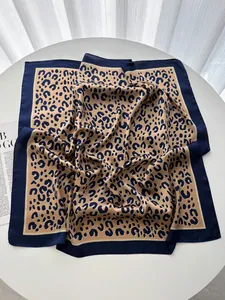 Dettaglio foulard in seta con stampa leopardata e bordo blu scuro su superficie