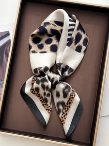 Close-up of leopard print silk scarf tied in a bow on a brown decorative tray