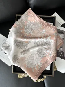 Detailed close-up of pink silk square scarf with floral print on a black tray