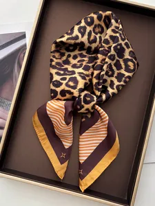 Détail d'un foulard en soie imprimé léopard et rayures dans un plateau de présentation chic