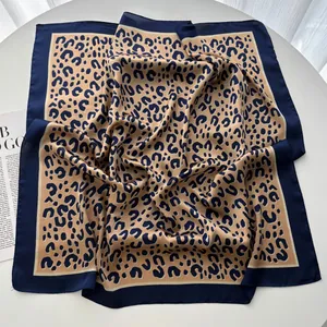 Dettaglio di foulard in seta sintetica leopardata con bordo blu navy e finitura satinata