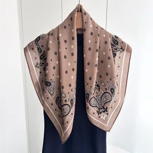 Brown paisley square silk scarf with floral patterns on a hanger with a black sweater