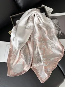Detailed view of floral silk scarf in soft pink and white draped on leather