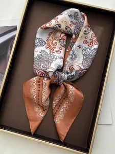Detail of vintage paisley pattern silk scarf with orange and beige tones in a gift box