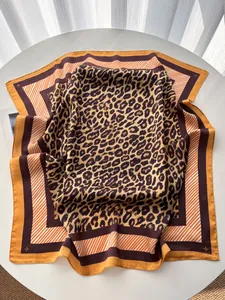 Détail du foulard en soie léopard avec bordures orange et texture satinée classique