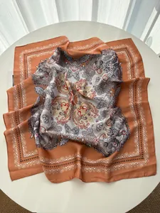 Detailed view of large paisley print silk scarf with warm orange and beige ethnic patterns