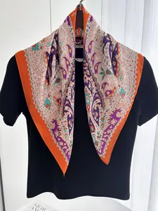 Macro detail of high-quality paisley print satin square scarf with vibrant orange borders