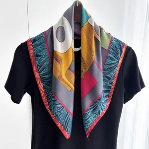 Elegant silk scarf with colorful tropical leaf prints and geometric patterns on a black shirt